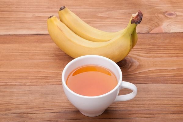 Canela com chá de banana e um cacho de bananas atrás