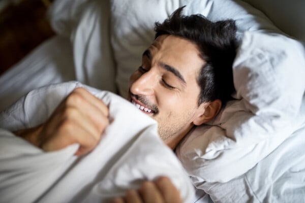 Homem sorrindo deitado na cama