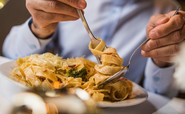 Imagem aproximada de homem comendo um prato de macarrão