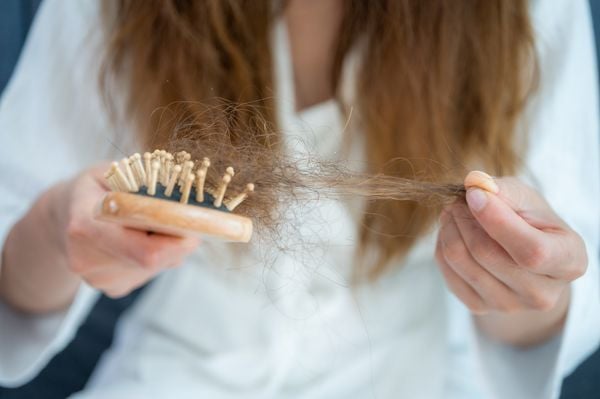 Mulher segurando escola e tufo de cabelo