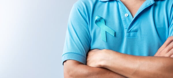 Homem de camisa azul posa com símbolo da campanha Novembro Azul