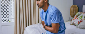 Homem com dor de barriga sentado na cama